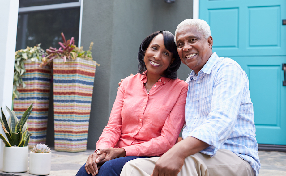 Senior couple sit on steps outside their house